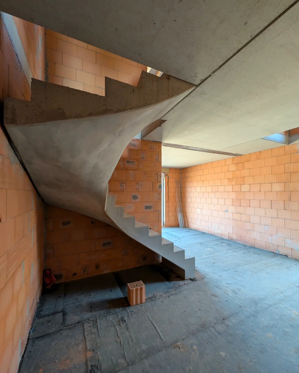 Geschwungene Betontreppe im Rohbau des Musterhauses am Kümmelsberg